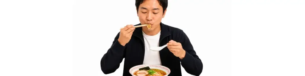 白背景の横長画像。黒系のジャケットと白いTシャツを着た男性が、ラーメンの丼を前に自然な姿勢で座っている。右手の箸で一口サイズの麺を口元へ運び、ちょうど食べているところが描かれている。左手には空の白いレンゲを持ち、口元よりかなり下、胸元あたりの高さに構えている。丼はカウンターの上に置かれ、男性は丼に顔を近づけすぎず、無理のない食事姿勢を保っている。ラーメンは醤油味で、チャーシュー、ネギ、海苔が見える。